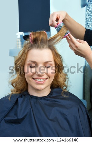 stylist putting hair rollers in woman hair
