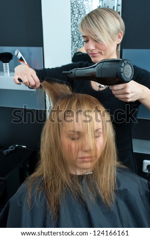 hair stylist drying woman hair in salon