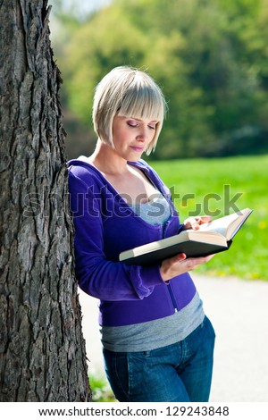 attractive adult woman reading book outside