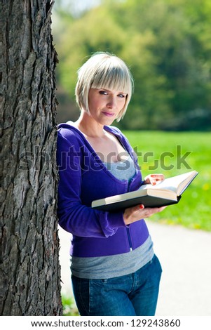 attractive adult woman reading book outside
