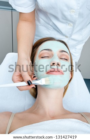 woman in spa applying beauty mask on her face