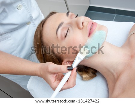 woman in spa applying beauty mask on her face