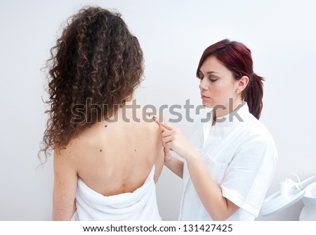 dermatologist doctor inspecting woman skin for moles and melanoma