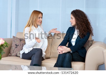 Two Woman Friends On The Sofa Talking