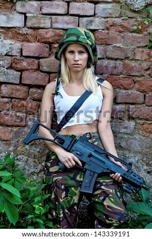Beautiful army girl with rifle in camouflage clothes
