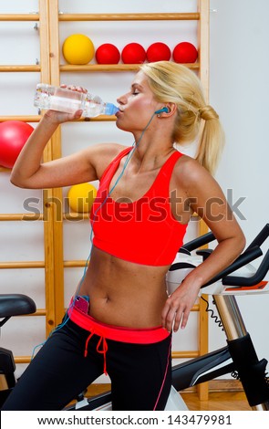 attractive woman drinks water from bottle in gym