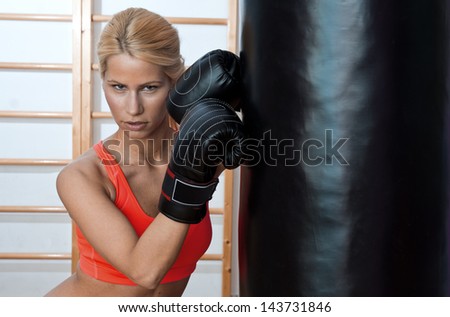 attractive woman boxer in gym with boxing gloves and bag