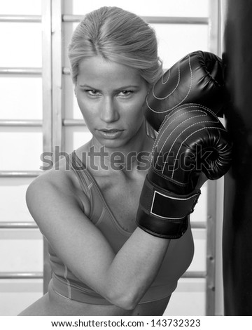 attractive woman boxer in gym with boxing gloves and bag