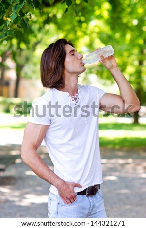 attractive fit man drinks water from plastic bottle