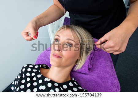 attractive blond woman having threading hair removal procedure