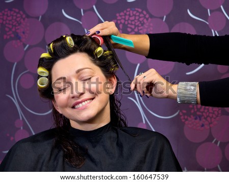 hairdresser stylist putting rollers in mature woman hair in salon