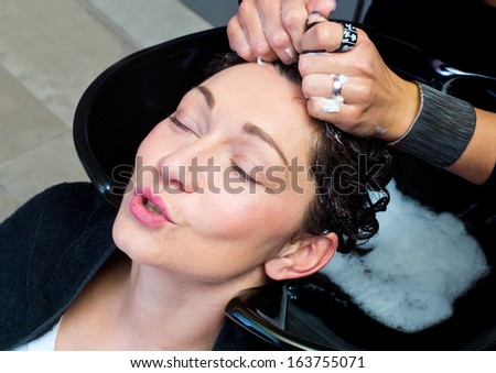 mature woman getting head massage and hair washed in salon