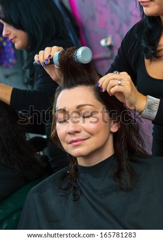 attractive mature woman in hair salon making new haircut by hairdresser