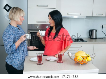 two attractive woman friends chatting in kitchen