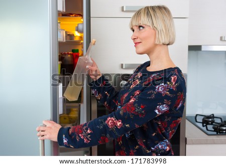 woman taking bottle from refrigerator at home