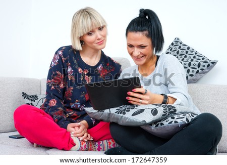 two attractive woman friends with tablet computer on the sofa