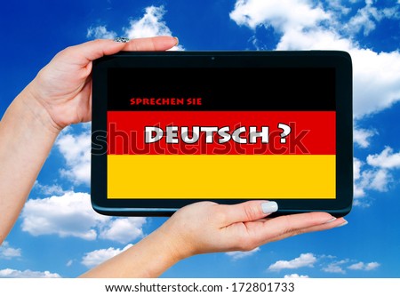 woman hands holding tablet with german language learning sign on the screen and blue sky in background