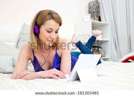 attractive woman in bed with laptop computer and headphones