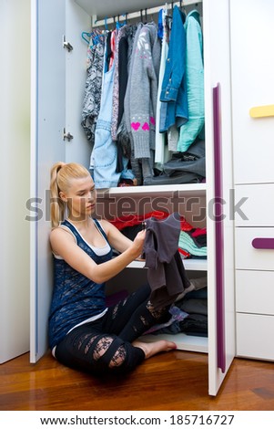 attractive teen girl choosing clothes in her room in front of closet
