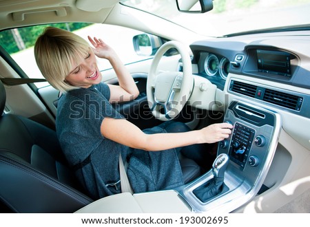 attractive blonde woman changing radio station in her car