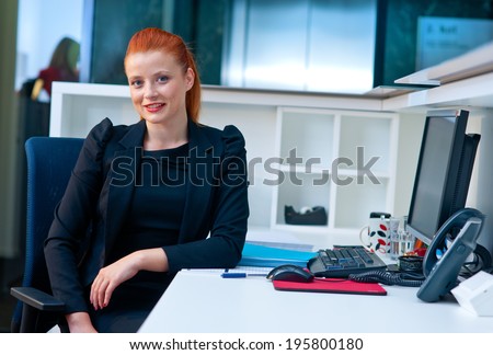 attractive modern businesswoman sitting and talking to phone in office cubicle workstation