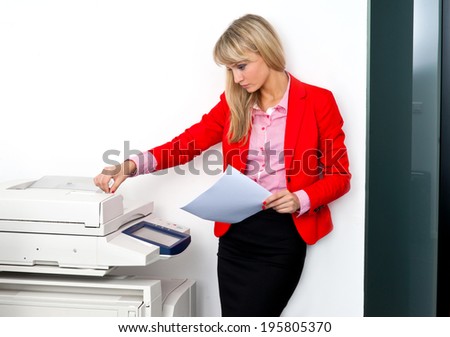attractive blonde business woman with documents standing next to printer