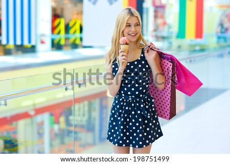 attractive teen blonde girl walking with ice cream and shopping bags