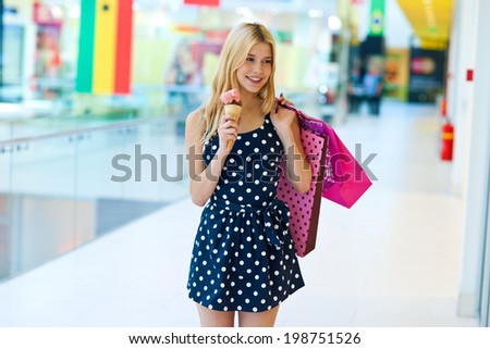 attractive blonde girl walking with ice cream and shopping bags