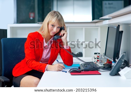 attractive blond business woman in office cubicle workspace with telephone