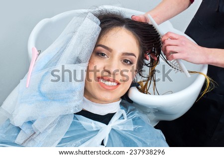 attractive woman in hair salon with coloring foil on her head washing