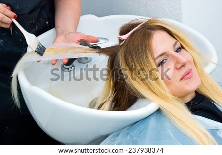 attractive woman in hair salon with coloring foil on her head and washing