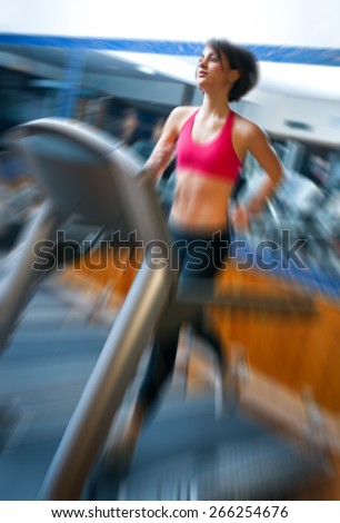 woman running in gym on automatic track machine, zoomed for dramatic presentation effect