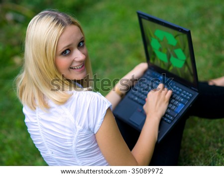 woman on grass with recycle logo on laptop screen