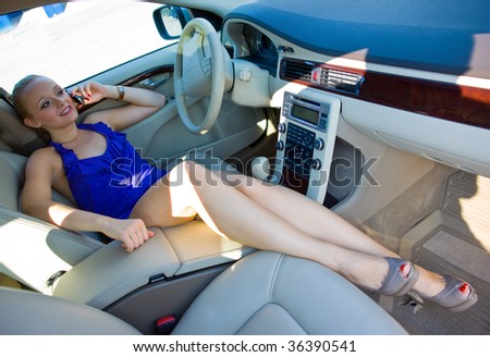 woman with beautiful legs talks on mobile phone in the car
