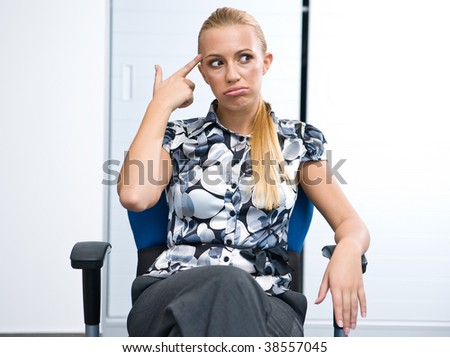 bored business woman sitting in office chair pointing finger to her head