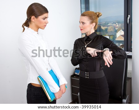 woman boss pointing at watch and showing time to her secretary