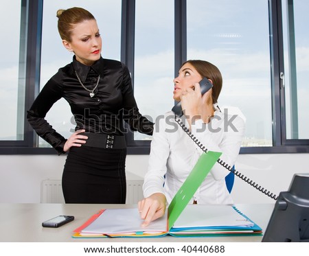 two businesswoman with documents and phone debating
