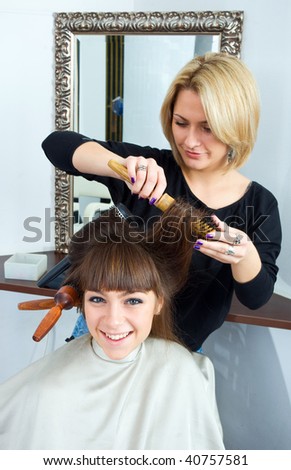 hair stylist and woman with brushes in her hair in hair salon