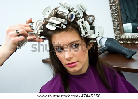 hair stylist put rollers in woman hair