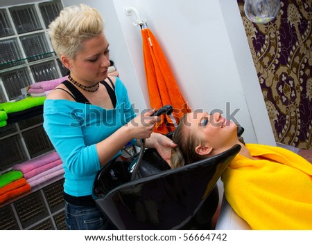 hair stylist washing woman hair in salon pool
