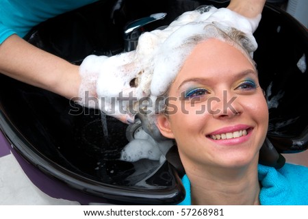 hair stylist washing woman hair in salon pool