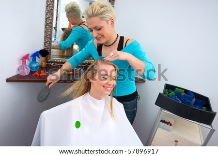stylist working on woman hair in salon