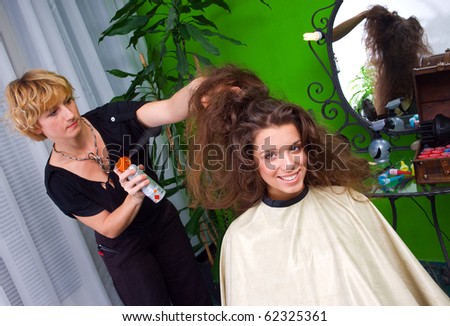 stylist spraying woman messy hair in salon