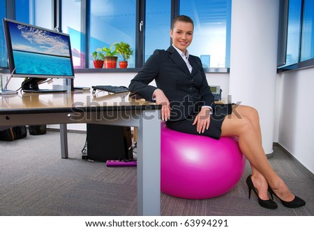 relaxed business woman sitting on pink pilates ball in the office