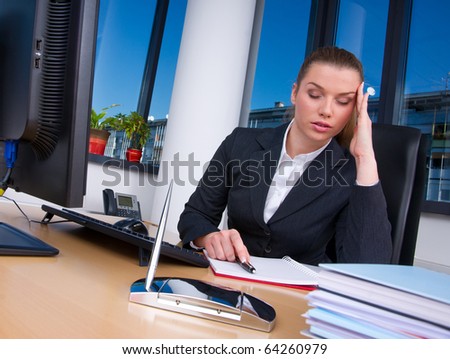 business woman heaving headache at office desk