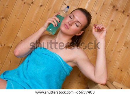 woman sweating in sauna and cooling herself with cold energy drink bottle