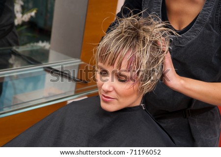 stylist drying woman hair in hairdresser salon