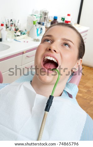 woman sitting in dentist chair with suction tube in her mouth