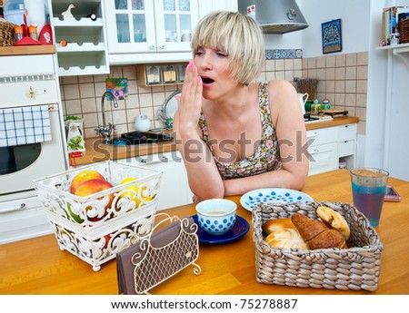 sleepy woman yawn at breakfast table in her kitchen
