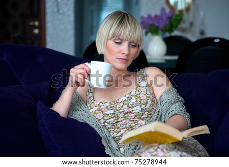 woman reading book nd drinking coffee while sitting on the sofa at home living room